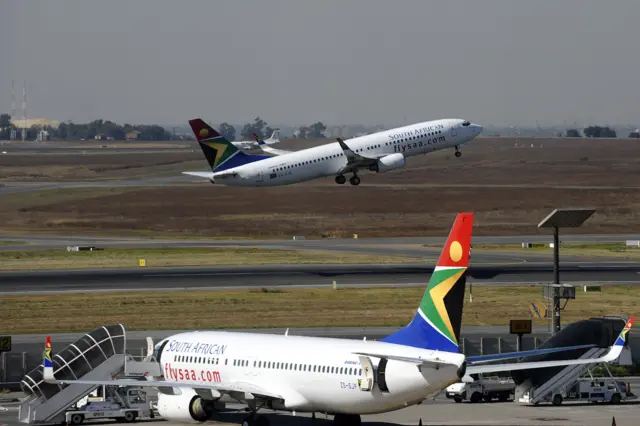 A South African airways flight takes off as another one is parked in a bay on the tarmac on May 25, 2010 at the Johannesburg O.R Tambo International airport in Johannesburg, South Africa.