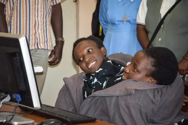 This handout photograph taken on September 13, 2017, and released by The Ruaha Catholic University (RUCU), shows conjoined twins Maria (L) and Consolata Mwakikuti as they react while looking at a computer in a computer laboratory of Ruaha Catholic University (RUCU) in Iringa, Tanzania, on their arrival day to attend the university