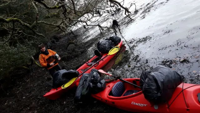 woman with two kayaks by a river