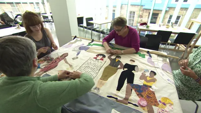 group of women sewing a banner