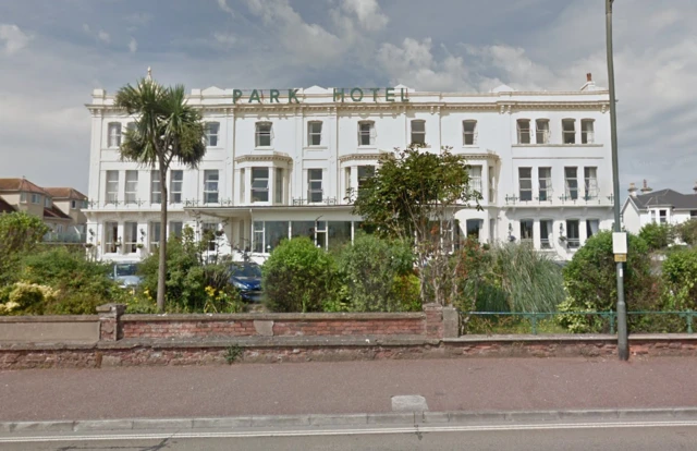 large white hotel with shrubbery in foreground