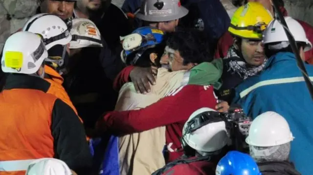 A Chilean miner hugs a rescuer after emerging from the mine