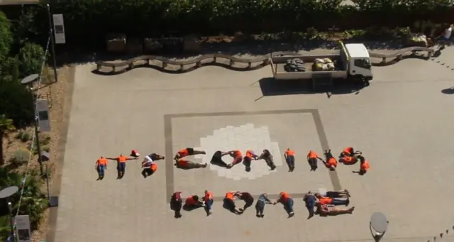 Students lying on the floor spelling out the phrase "It's coming home".