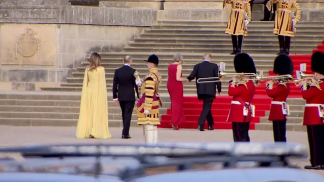 Theresa May holds Donald Trumps hand as he climbs the steps of the palace