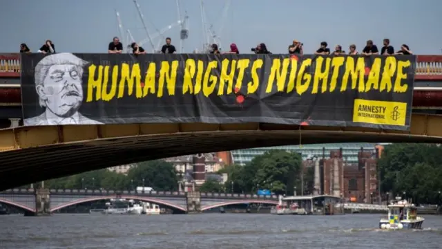 Human rights group Amnesty International drops a banner from Vauxhall Bridge opposite the US Embassy