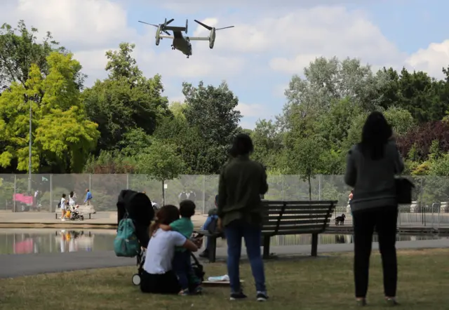 Families in Regent's Park watching a military helicopter overhead