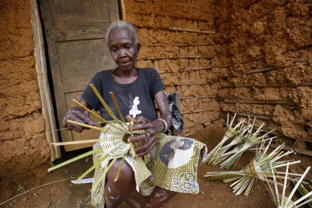 An elderly villager, Wrusayeworie Gbogde makes baskets, made of woven palm leaves and used to catch fresh water crabs, at her home in Malcolm Jay Town, Grand Bassa County, Liberia, 07 July 2018