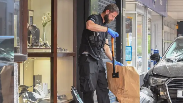 Police officer placing axe in a bag