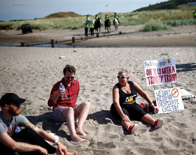 Demonstrators sit on the beach near Trump Turnberry