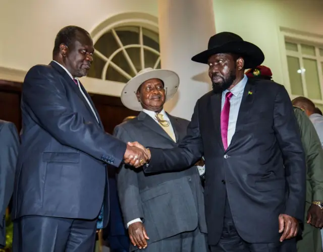 President of South Sudan, Salva Kiir (R) shakes hands with arch-rival South Sudan's opposition leader Riek Machar (L) during peace talks at Uganda's statehouse in Entebbe where they were received by Ugandan President Yoweri Museveni (C)