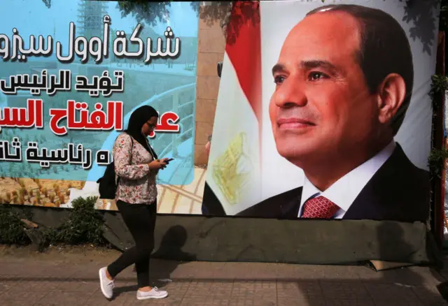 A woman walks past a campaign sign for Egyptian President Abdel Fattah al-Sisi one day before the presidential elections on March 25, 2018 in Cairo, Egypt.