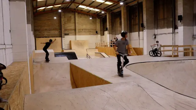 Skaters and scooter riders use the ramps at the park