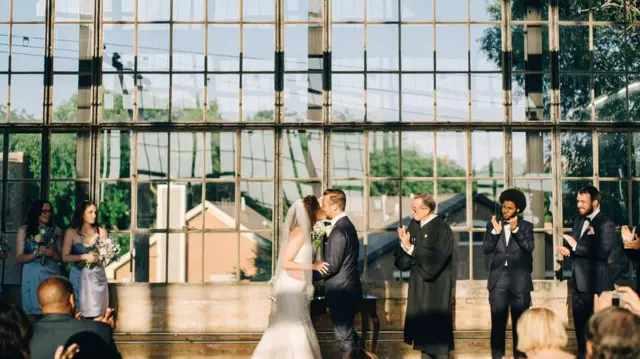 Two people kiss in a wedding ceremony