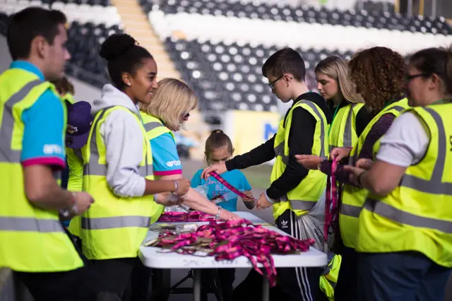 Volunteers in high vis vests sort through medals on a table