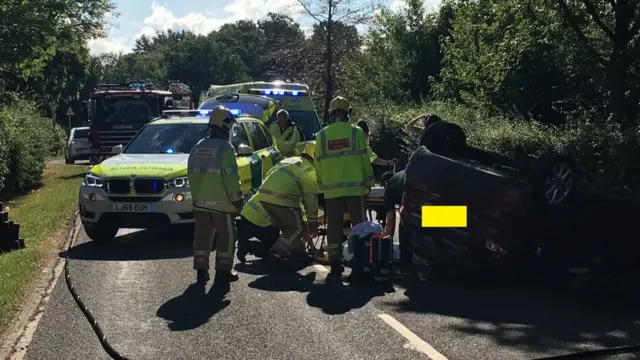 The overturned car surrounded by emergency services