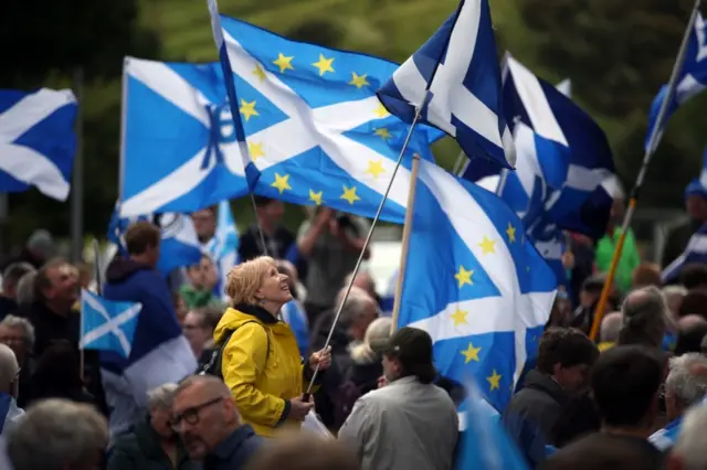 Woman holds a Scottish and EU flag