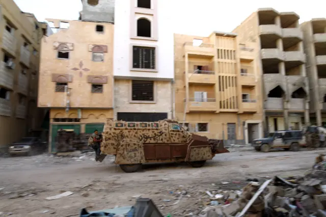 A picture taken on November 9, 2017 shows a member of the self-styled Libyan National Army, loyal to the country's east strongman Khalifa Haftar, riding in the back of an armoured vehicle as it advances through a street in Benghazi's central Akhribish district following clashes with militants.