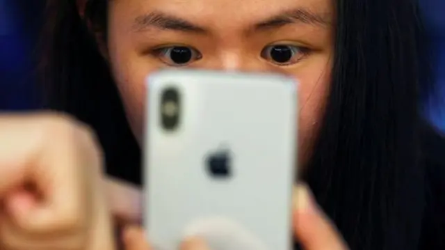 A woman looking at an iPhone X