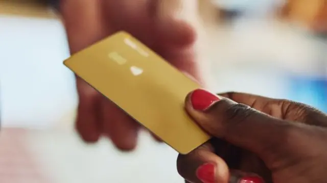 Handing a debit card to a sales assistant