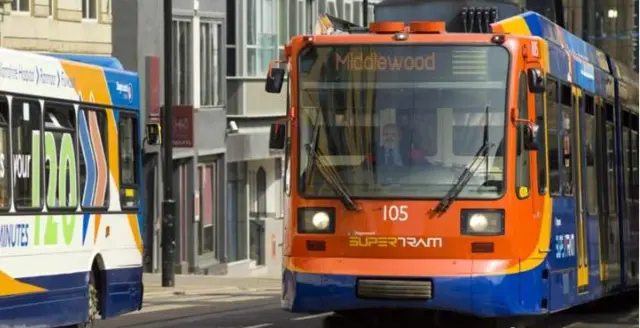 A supertram drives next to a bus