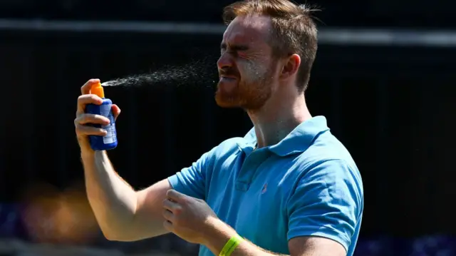 Man sprays suncream at Wimbledon