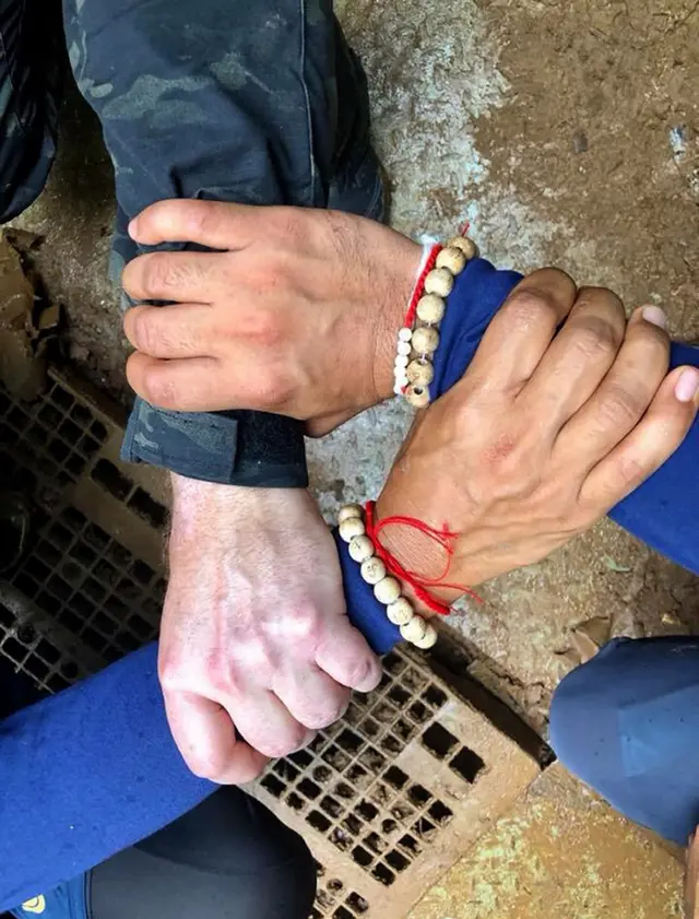 Thai Navy SEALS and international rescuers clasping hands