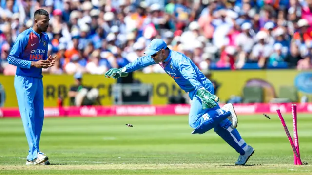 MS Dhoni falls over the stumps after catching Eoin Morgan