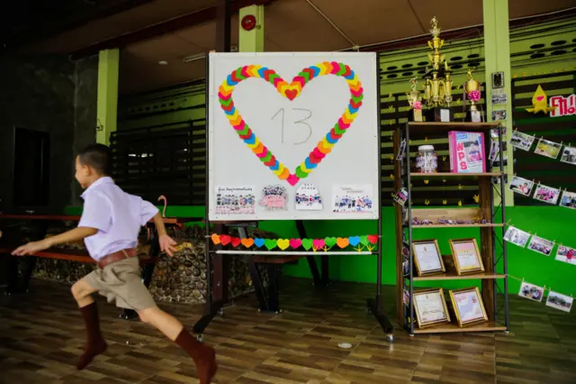 Classmates of Adul, one of the boys trapped in Tham Luang Nang Non cave, visit a tribute for the Wild Boars soccer team