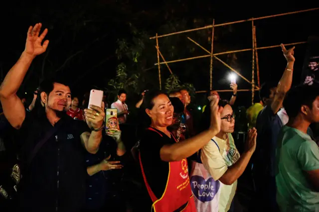 Onlookers watch and cheer as ambulances transport a number of the rescued schoolboys from a helipad to a hospital