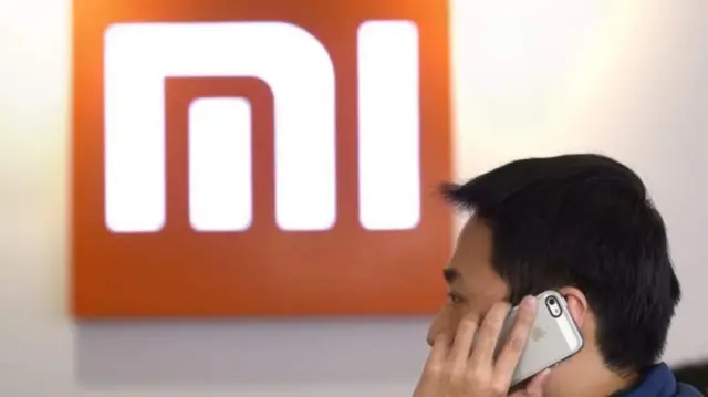 Man on phone in front of Xiaomi logo