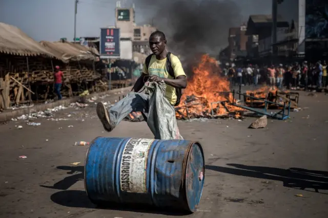 A supporter of Zimbabwean opposition MDC Alliance push a barrel in front of a fire in Harare on August 1, 2018