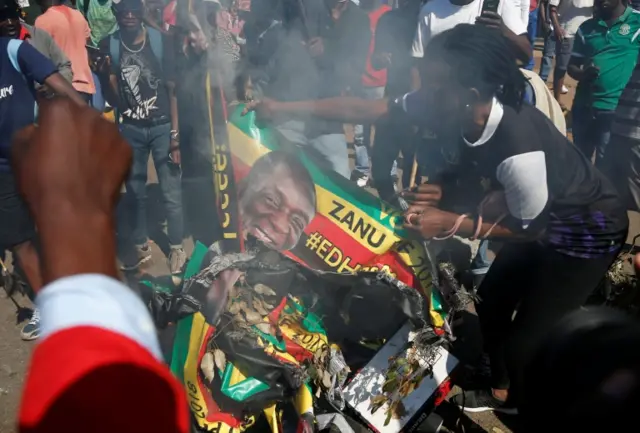 Supporters of the opposition Movement for Democratic Change party (MDC) of Nelson Chamisa burn an election banner with the face of Zimbabwe"s President Emmerson Mnangagwa in Harare, Zimbabwe, August 1, 2018.