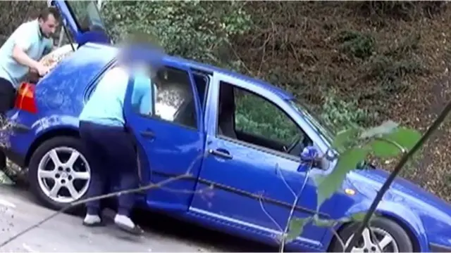 Two people remove an item from a car