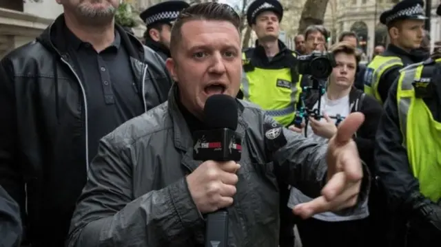 Tommy Robinson addressing a crowd surrounded by police officers