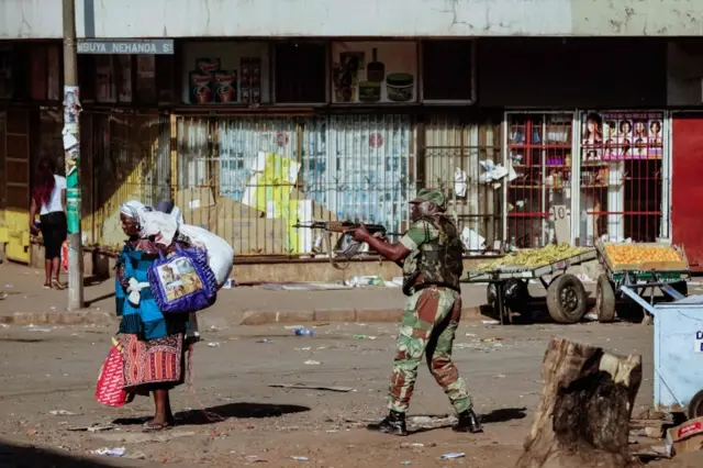 A vendor scurries for cover with her wares as soldiers disperse demonstrators on August 1 2018, after protests erupted over alleged fraud in the country"s election