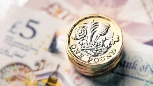 Pile of £1 coins on bank notes