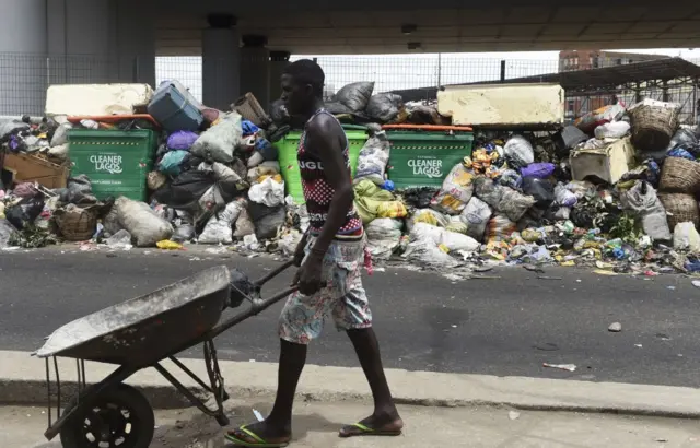 A man passes a pile of waste deposited on a roadside in Lagos on February 27, 2018