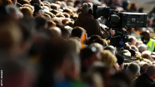 A camera operator within football supporters