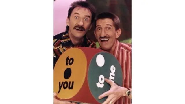 Barry and Paul with a dice showing their catchphrase