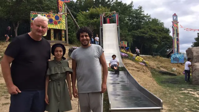 People pose in front of a slide