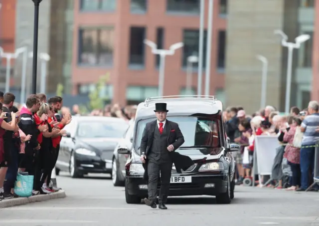 The cortege carrying the coffin of Barry Chuckle arrives at the New York Stadium.