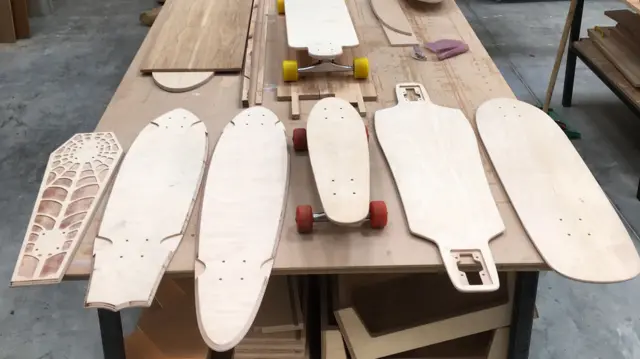 Blank skateboards lie on a workbench