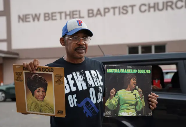 A fan holds up albums outside the New Bethel Baptist Church to pay his respects to the late Aretha Franklin in Detroit