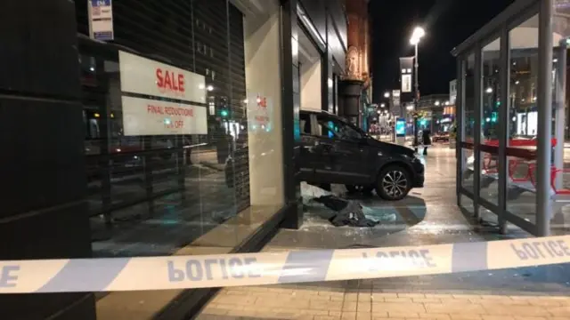 The car sticking out of the front window of the store