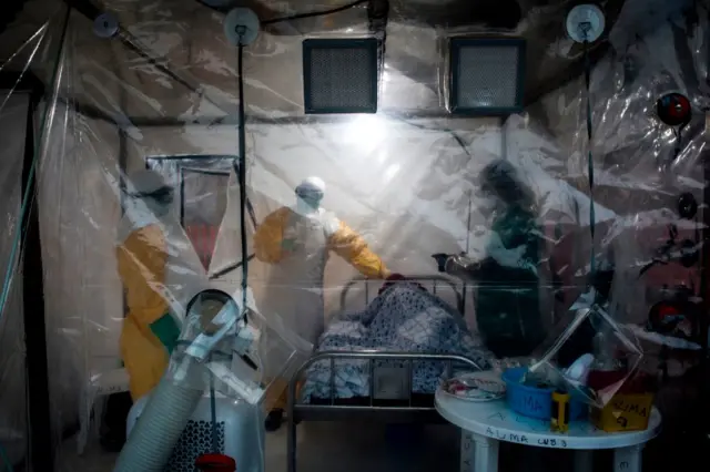 Three medical workers check on an Ebola patient in a Biosecure Emergency care Unite (CUBE) on August 15, 2018 in Beni.