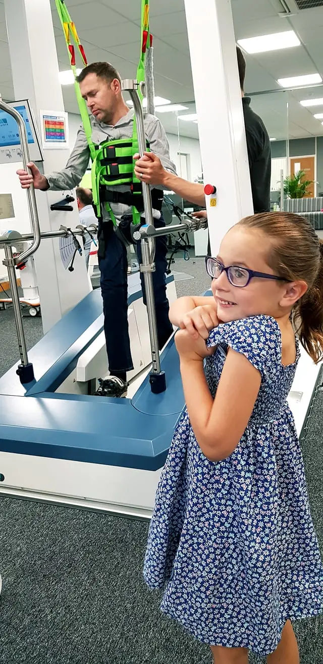 Little girl sees her dad walking with the aid of specialist equipment