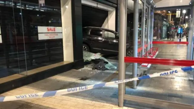 The car sticking out of the shop window.