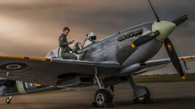 A man on his phone next to the spitfire