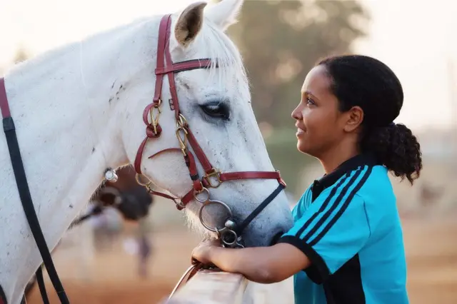 Woman in profile looking at a horse