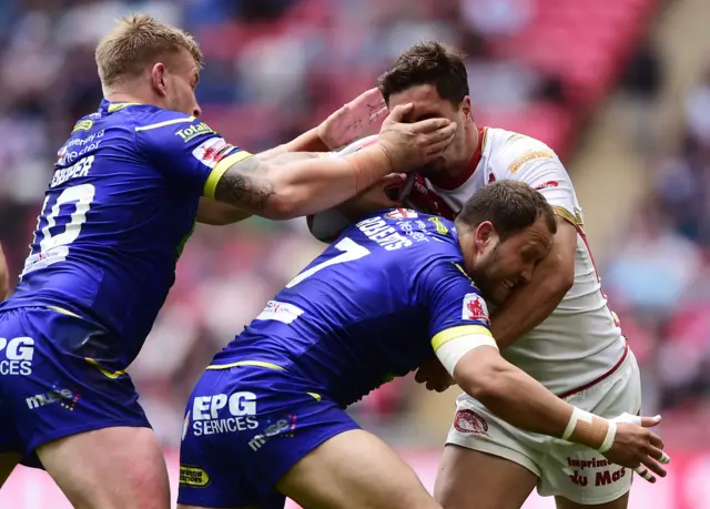 Tony Gigot of Catalan Dragons is tackled by Mike Cooper and Tyrone Roberts of Warrington Wolves